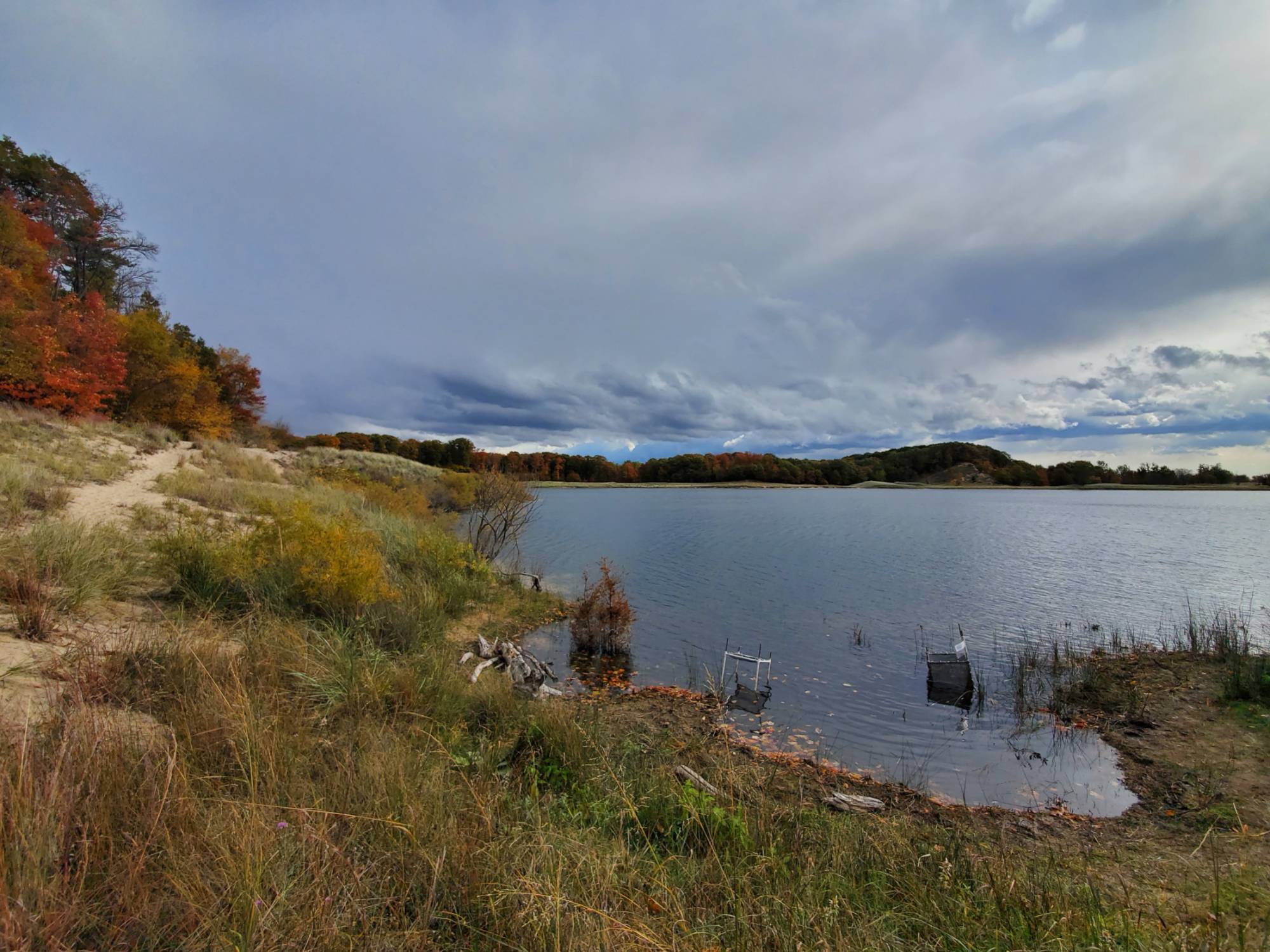 A grass-covered sand dune by a lake.